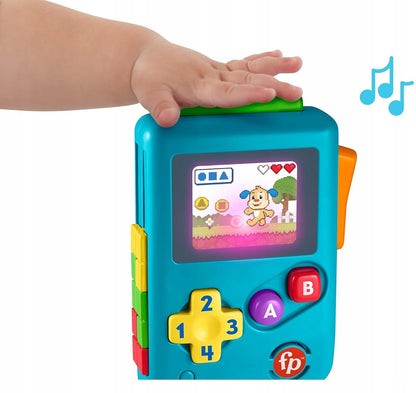 Dłoń naciskająca zielony element konsoli Fisher-Price Lil Gamer; obok zabawki widoczne są graficzne nuty.