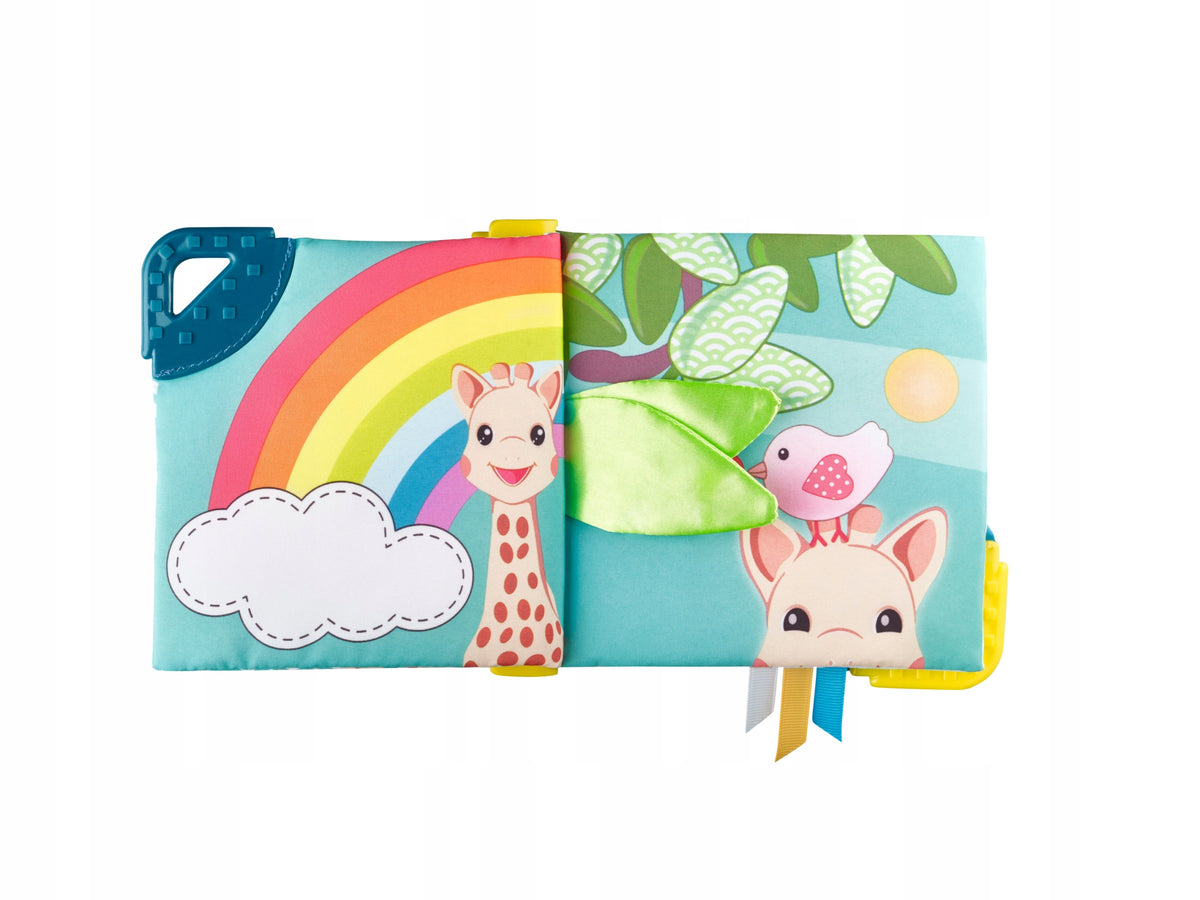 Otwarta książeczka Sophie la girafe z tęczą, żyrafą i zielonym materiałowym elementem.